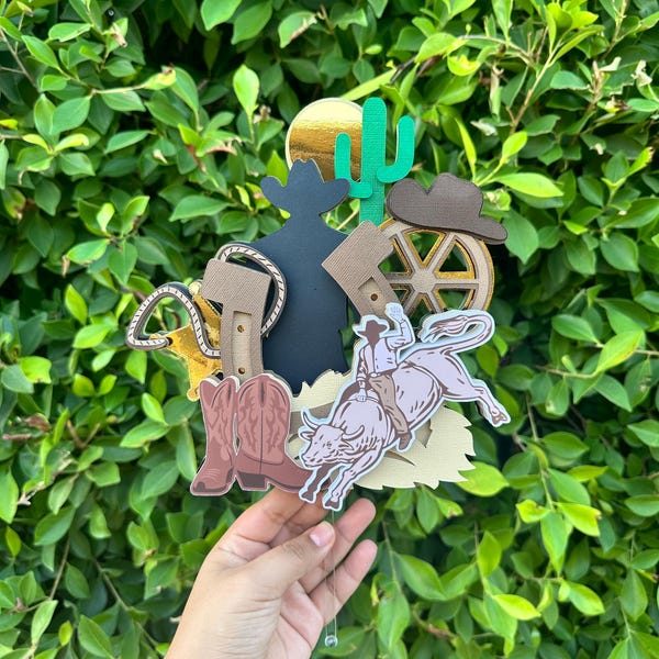 Western cowboy rodeo cake topper held against greenery